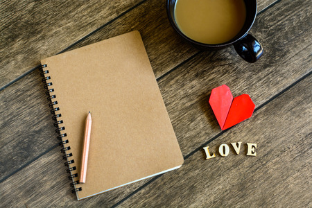 Cup of coffee with Blank notepad with copy space and red heart shape on wooden backgroundの写真素材