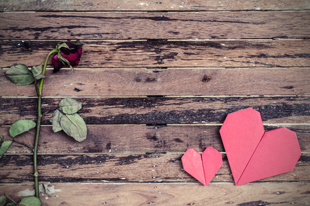 Withered rose and red heart shape on wooden background, Vintage styleの写真素材