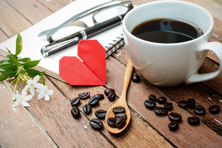 Cup of coffee and beans with notebook, flower, red heart shape and soft light, Vintage styleの写真素材