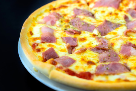Close up of Ham pizza isolated on black backgroundの写真素材