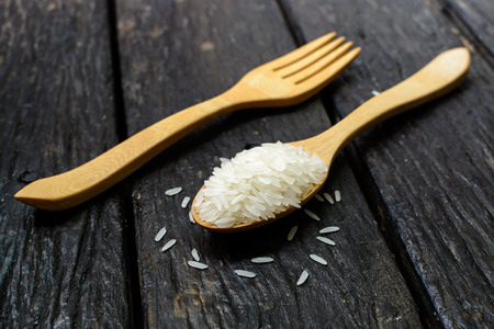 Rice in wooden spoon on old wooden backgroundの写真素材