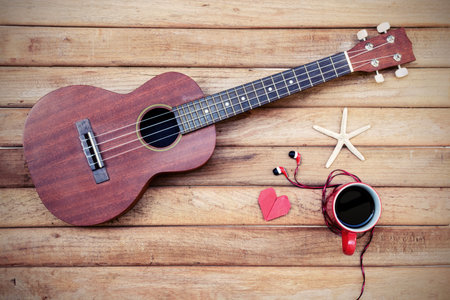 Cup of coffee with ukulele on old wooden background, Vintage style