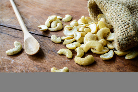 Close up of Cashew nuts with wooden spoon on old wood texturedの写真素材