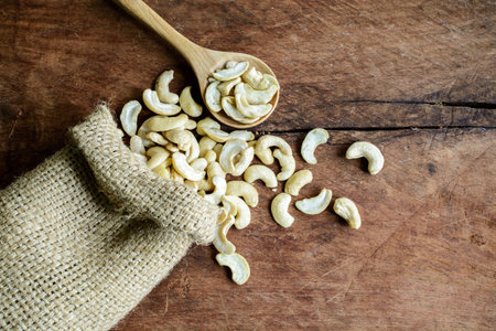 Cashew nuts with wooden spoon on old wood textured backgroundの写真素材