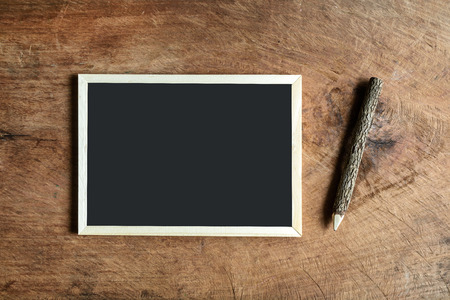Blank blackboard and wooden pencil on old wooden backgroundの写真素材