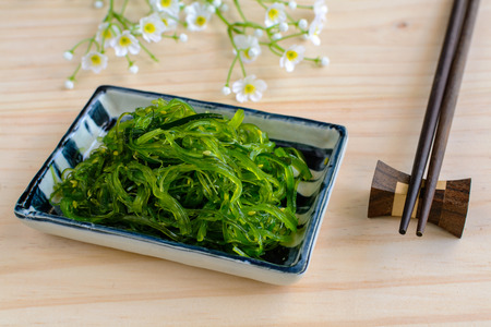 Traditional Japanese seaweed salad with chopsticks on wooden tableの写真素材