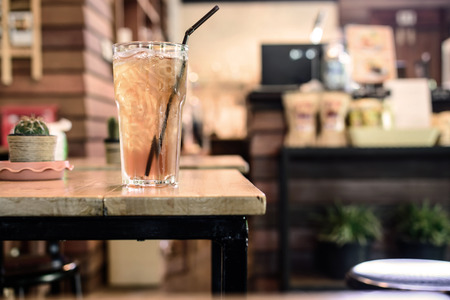 Glass of ice tea on wooden table in coffee shop, Vintage toneの写真素材
