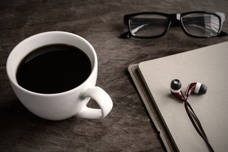 close up of earphone with coffee and notebook on old wooden table, Vintage toneの写真素材