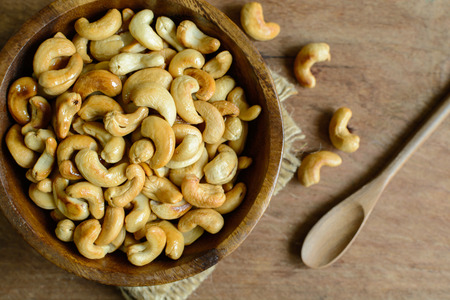 Fried cashew nuts with wooden spoon on sackclothの写真素材