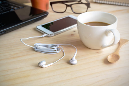 earphone with cup of coffee on wooden deskの写真素材