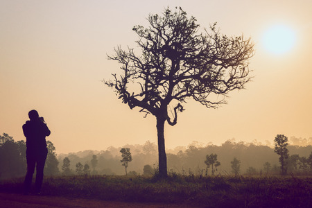 silhouette of photographer taking picture of landscape during sunriseの写真素材