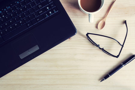 Laptop and cup of coffee on wooden desk, Vintage tone