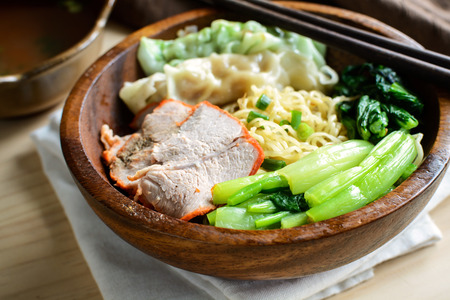Egg chinese noodles with roast pork and dumpling in wooden bowlの写真素材