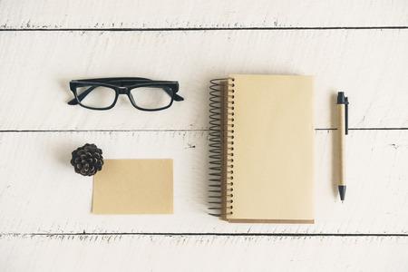 Blank note book with eye glasses and pen on white wooden background, Top view, Vintage toneの写真素材