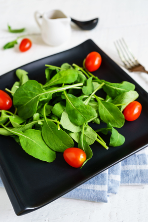 Rocket salad with cherry tomatoes on white wooden backgroundの写真素材