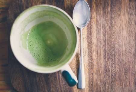 Empty matcha latte green tea cup on a wooden board, Vintage tone
