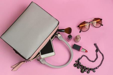Woman handbag with makeup and accessories isolated on pink backgroundの写真素材