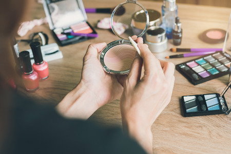 Girl doing makeup on dressing table with cosmeticsの写真素材
