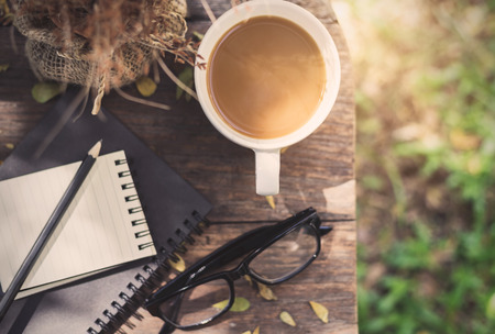 Notebook with cup of coffee on wooden table in the garden, Vintage toneの写真素材