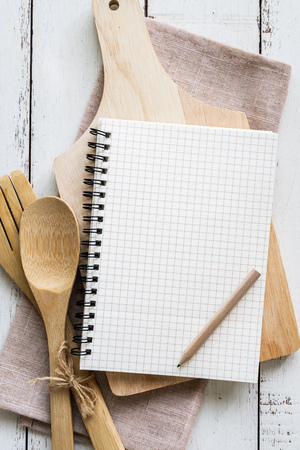 Blank notebook with wooden utensil on white wooden table with copy space, Top viewの写真素材