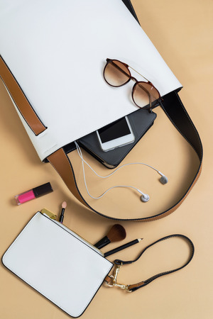 Fashion woman handbag with cellphone, makeup and accessories isolated on color background, Top viewの写真素材