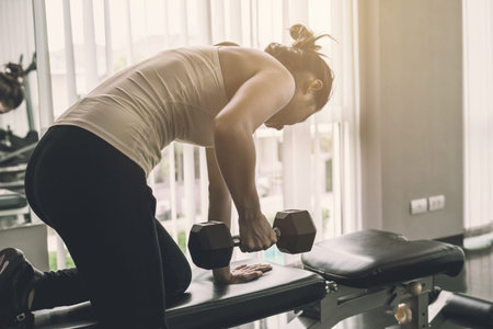 Young asian women lifting dumbbell in sport gym