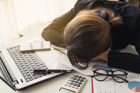 Overworked and tired businesswoman sleeping on laptop in workplaceの写真素材