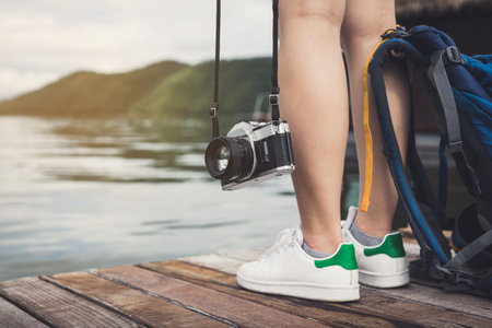 Young traveler standing and looking at the nature with camera and backpackの写真素材