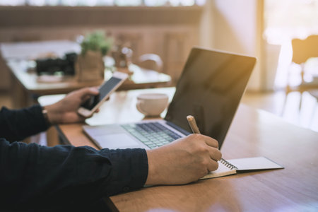 Businessman using laptop and smart phone in coffee shop