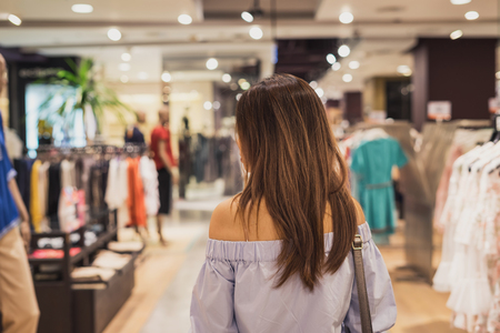 Young asian woman walking in clothes store at the mallの写真素材
