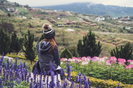 Young woman traveler in the flower field on the mountain looking view of natureの写真素材