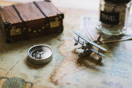 Vacation money saving in a glass with toy airplane and compass on map, Travel conceptの写真素材