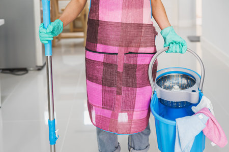Young woman cleaning floor in living room with mop and bucket, Housework conceptの写真素材