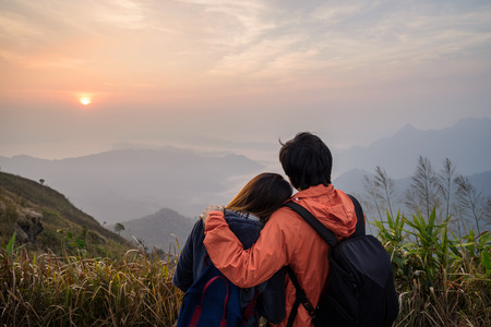 Loving couple embracing on the mountain against beautiful landscape at sunset.の写真素材
