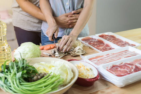 Young asian couple cutting vegetable in the kitchen, prepare the ingredient for cookingの写真素材