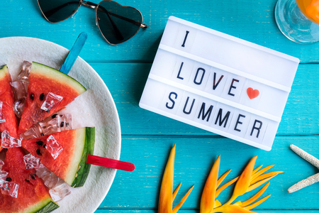 Women's casual clothes with accessories items and tropical fruits and flowers on white wooden background, I love summer conceptの写真素材
