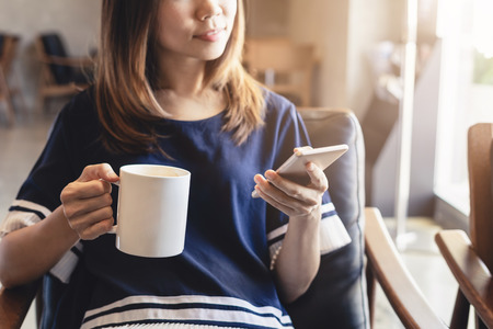 Young woman using smart phone in coffee shop drinking coffeeの写真素材