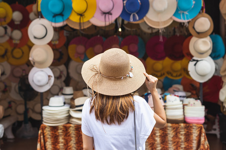 Young woman traveler looking for hat at the local market in Thailandの写真素材