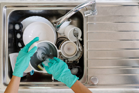 Young woman with gloves washing dishes in the kitchen, House work concept