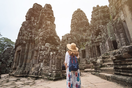 Young woman traveler visiting in Bayon temple at Angkor Wat complex, Khmer architecture heritage in Siem Reap, Cambodiaの写真素材