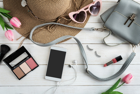 Woman accessories with make up, cosmetics, brushes and smart phone on white wooden background, Top viewの写真素材