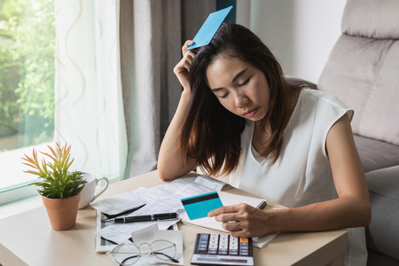 Stressed young woman checking bills, taxes, bank account balance and calculating expenses in the living room at homeの写真素材