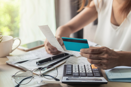 Young woman checking bills, taxes, bank account balance and calculating credit card expenses at homeの写真素材