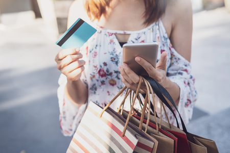 Young woman using smartphone with shopping bags and credit card at shopping mall on black friday, Woman lifestyle conceptの写真素材