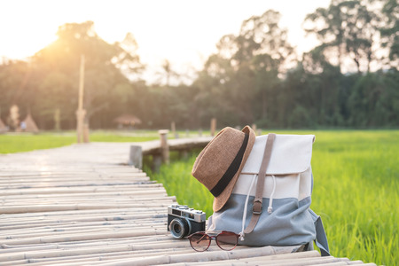 Backpack with hat and camera on bamboo path at green paddy field, Travel conceptの写真素材
