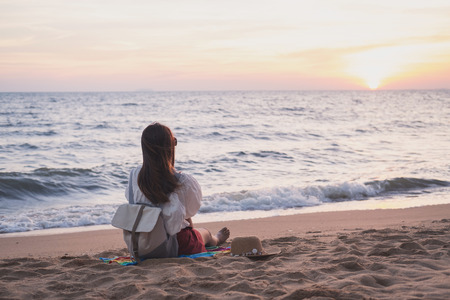 Young traveler woman relaxing on tropical beach at sunset, vacation and summer conceptの写真素材