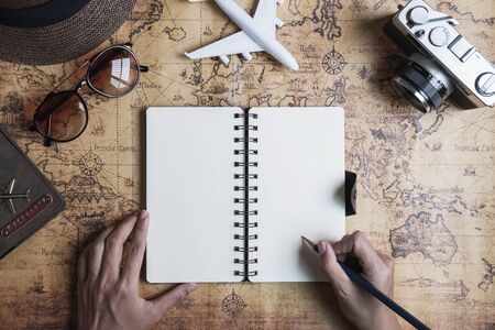 Retro camera with toy plane and travel dairy on old world map background with copy space, Travel conceptの写真素材