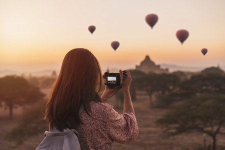 Young woman traveler enjoying with balloons over ancient pagoda at Bagan, Myanmar at sunrise