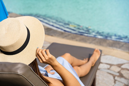 Young woman traveler enjoying a summer vacation at swimming pool in tropical resort near the beach,...