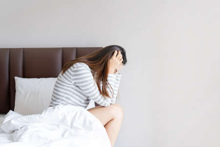 Lonely young woman depressed and stressed sitting in the bedroom, Negative emotion and mental health conceptの写真素材